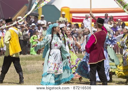Men and women in national costumes dance traditional folk dances