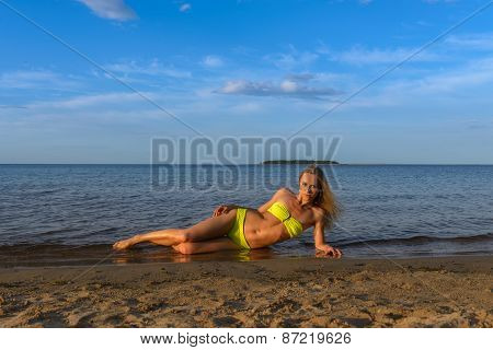 young woman in green bikini posing on a beach
