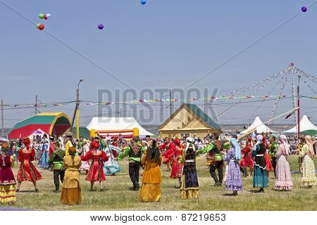 Men and women in national costumes dance traditional folk dances