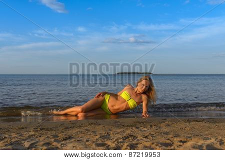 young woman in green bikini posing on a beach