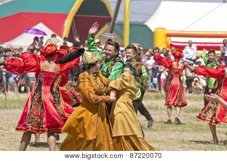 Men and women in national costumes dance traditional folk dances