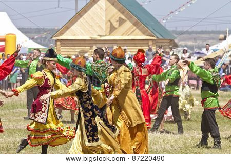 Men and women in national costumes dance traditional folk dances