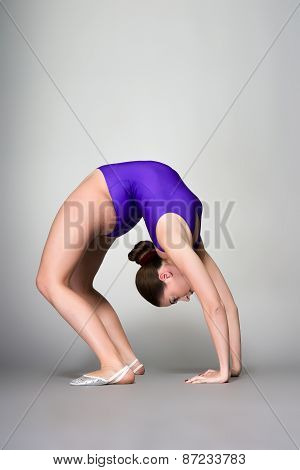Young Female Contortionist In Purple Leotard On Dark Background