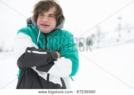 Young man in jacket shivering in snow