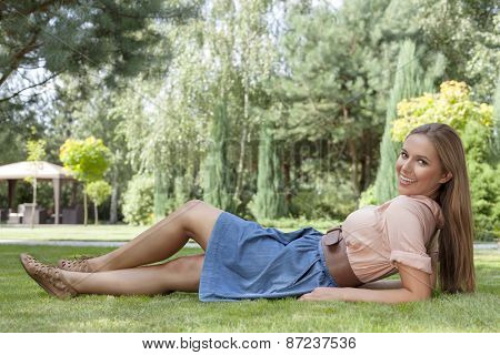 Full length of beautiful young woman reclining on grass in park