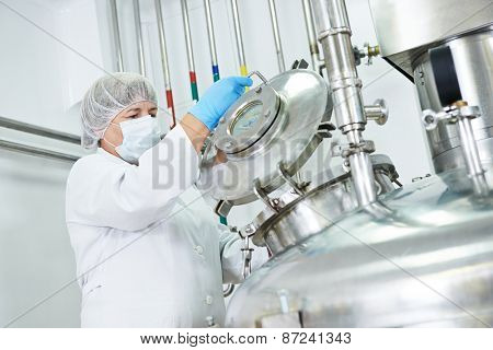 female worker operating pharmaceutical factory equipment mixing tank on production line in pharmacy industry manufacture factory