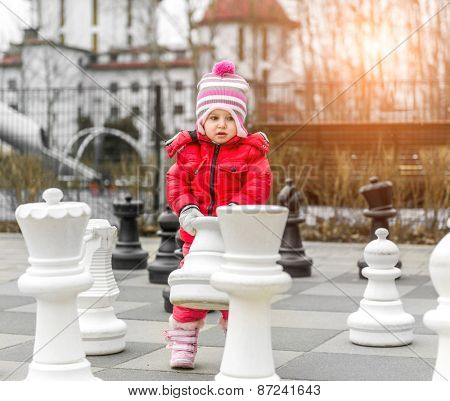 Chess game with giant chess piece. Girl playing strategic outdoor game