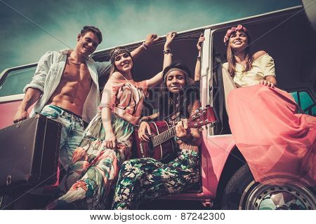 Multi-ethnic hippie friends with guitar on a road trip