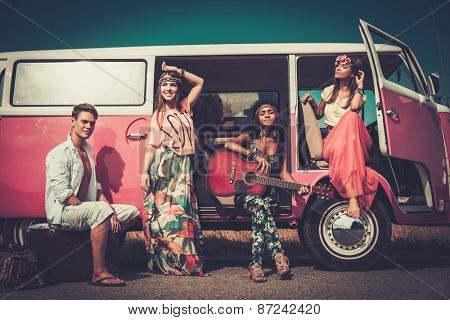 Multi-ethnic hippie friends with guitar on a road trip