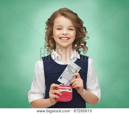 finances, childhood, school, people and education concept - happy little girl with purse and paper euro money over green chalk board background