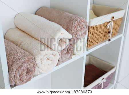 Rolled towels with wicker basket on shelf of rack background