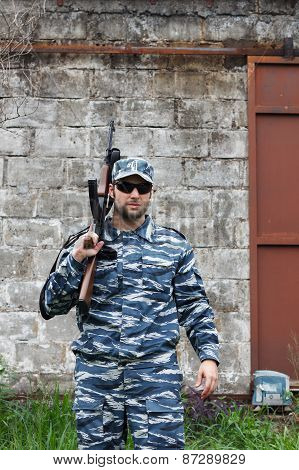 Caucasian Military Man With Black Sunglasses In Urban Warfare Holding Rifle On Shoulder