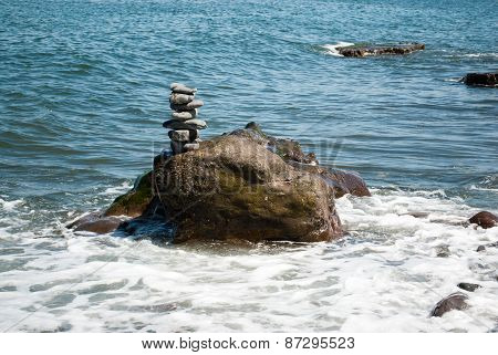 Stacked Pebble Tower being Washed by Wave
