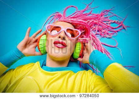 Ultra trendy DJ party girl in bright clothes, headphones and with bright dreadlocks. Disco, party. Show business. Bright fashion.