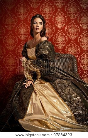 Full length portrait of a beautiful young lady in the lush expensive dress posing over vintage background. Renaissance. Barocco. Fashion.