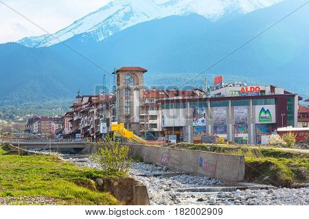 Bansko, Bulgaria April 14, 2017: Spring view with river Glazne, mountains landscape, Bansko Mall and house tower