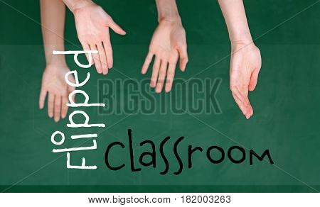 Flipped classroom concept. Inversed children's hands on blackboard background