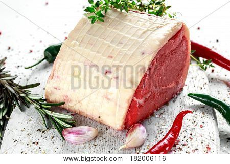 a pieces of fresh raw meat, beef slab, decorated with greens and vegetables