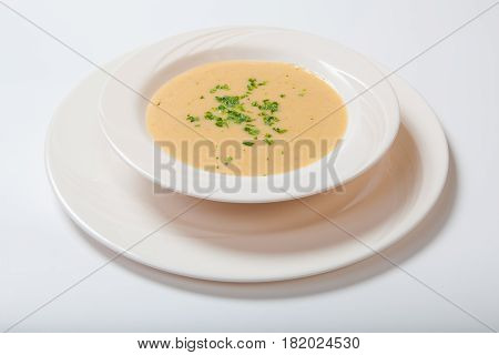 Creamy Vegetables Soup With Fresh Herbs In A White Bowl