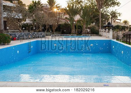 Empty swimming pool in hotel with metal ladder.