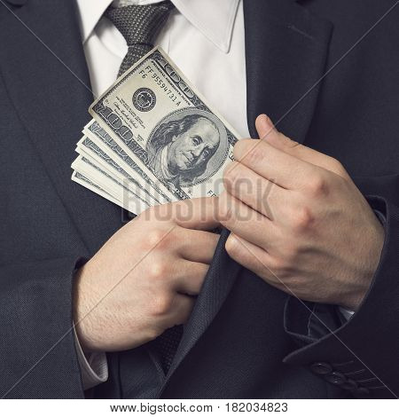 Detail of a man in a suit placing money in his jacket pocket. Selective focus