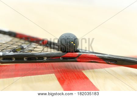 squash racket and ball on the floor near red lines. Closeup of racquetball equipment on the court. Photo with selective focus. Sport, games on the court, healthy lifestyle concept