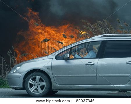 The driver of the car looks at huge fire