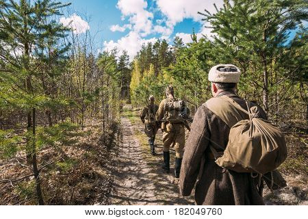 Group Of Re-enactors Dressed As Soviet Russian Red Army Infantry Soldiers Of World War II Marching Along Forest Road At Spring Season.