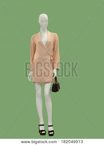 Full-length female mannequin dressed in pink dress isolated on green background.