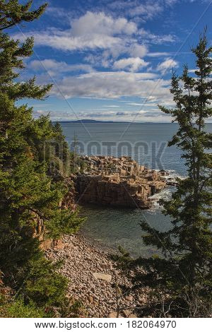 Rocky shore line along Atlantic coast in Maine. Framed by pine trees.
