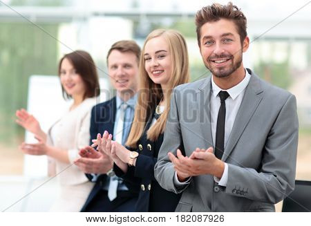 Business colleagues looking at camera and applauding in the offi