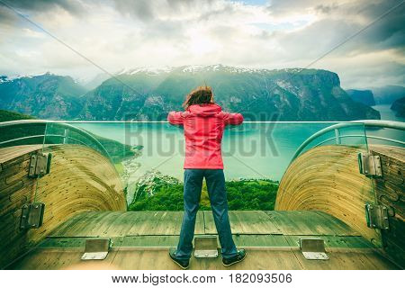 Tourist woman on Stegastein viewpoint enjoying Aurland fjord view in evening time Sogn Og Fjordane Norway