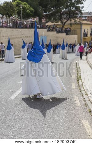Penitents with white tunic and blue layer during atonement station,  procession of Holy Week on Sunday of resurrection Linares Andalusia Spain