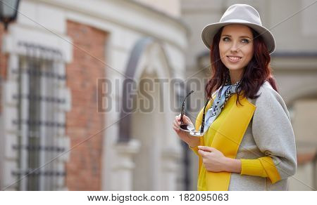 Close-up Fashion woman portrait of young pretty trendy girl posing at the city in Europe,summer street fashion,holding retro fedora hat popular until the 60s.laughing and smiling portrait.trendy