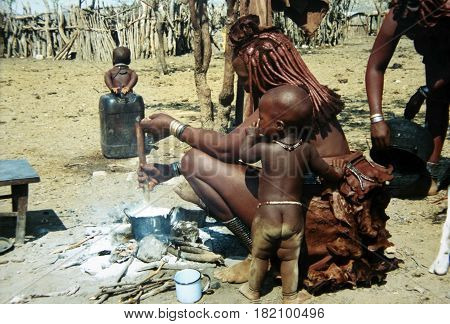 Khorixas, Namibia-April 17th 2017: picture of 2 women of the Himba tribe who are cooking. Two little kids walk around.