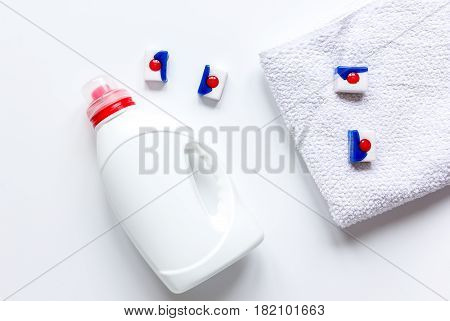 laundry set with pastel towels and detergent plastic bottel on white table background top view