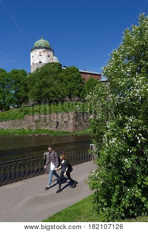 VYBORG, LENINGRAD OBLAST, RUSSIA - JUNE 6, 2015: People on the embankment against the tower of St. Olav of Vyborg Castle. The castle was founded in 1293