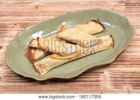 Delicious cheese blintz on green plate and wooden vintage tray