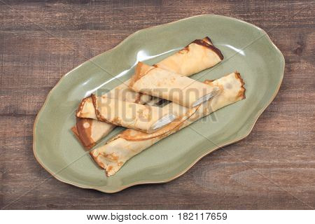 Delicious cheese blintz on green plate and wooden vintage tray