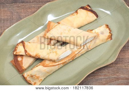 Delicious cheese blintz on green plate and wooden vintage tray