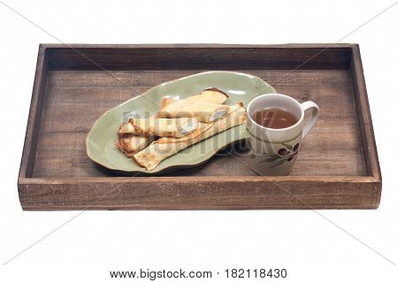 Delicious cheese blintz on green plate and cup of tea on wooden vintage tray