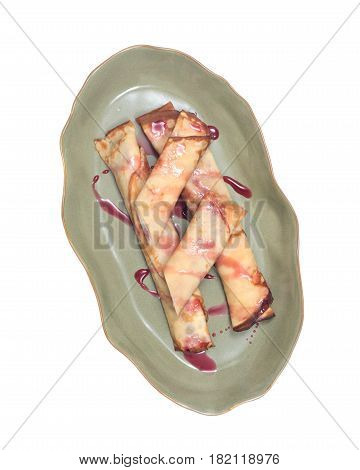 Delicious cheese blintz with raspberry syrup on green plate isolated on white background