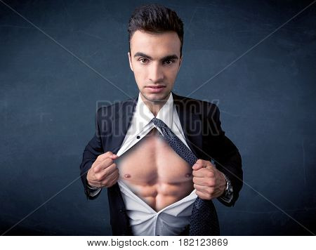 Businessman tearing off his shirt and showing mucular body concept on background