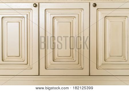 Close up of three white wooden doors of cupboard with metal knobs