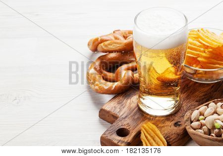 Lager beer and snacks on wooden table. Nuts, chips, pretzel. With copy space