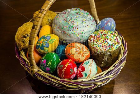 Easter cake with decorative bird and basket on wooden table
