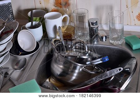 A Huge Pile Of Unwashed Dishes In The Kitchen Sink And On The Countertop