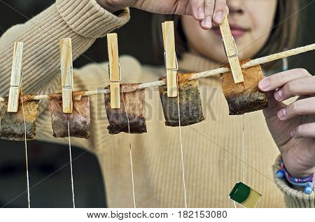 Girl is hanging used tea bags for drying and multiple use on the clothesline with clothes pegs