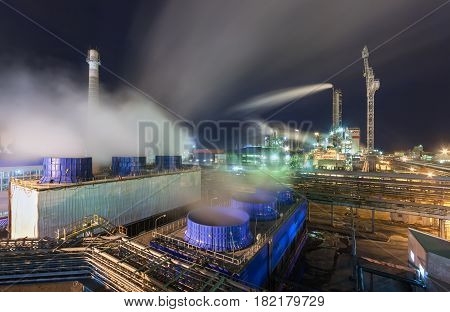 Chemical plant for production of ammonia and nitrogen fertilization on night time. Large cooling towers with steam next to the pipeline