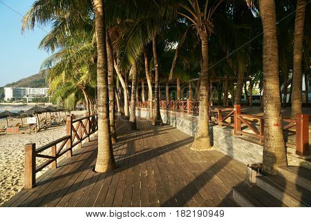 Morning tourist embankment with palm trees along the beach at Dadonghai Bay on Hainan Island, China